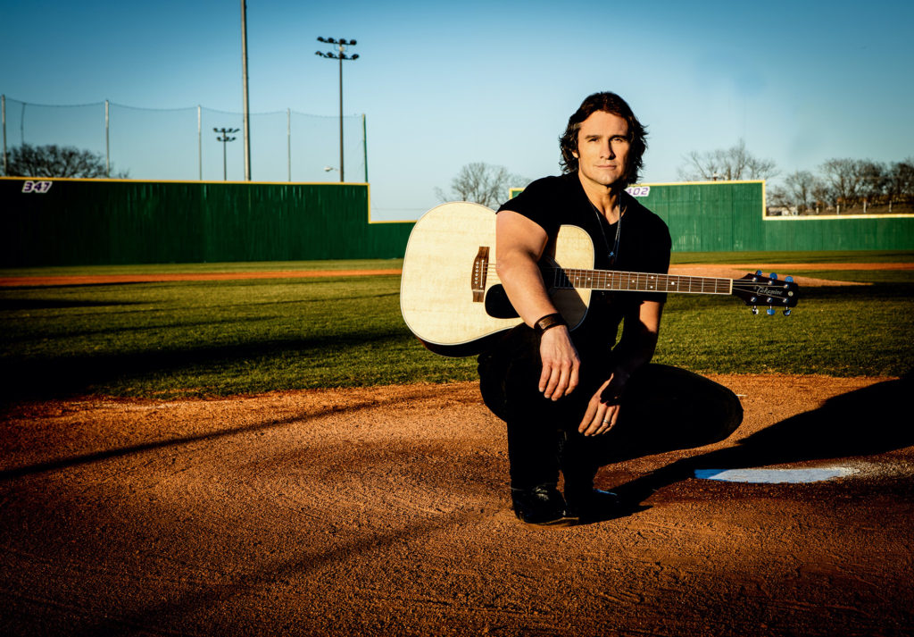 Joe Nichols with a guitar in a baseball field