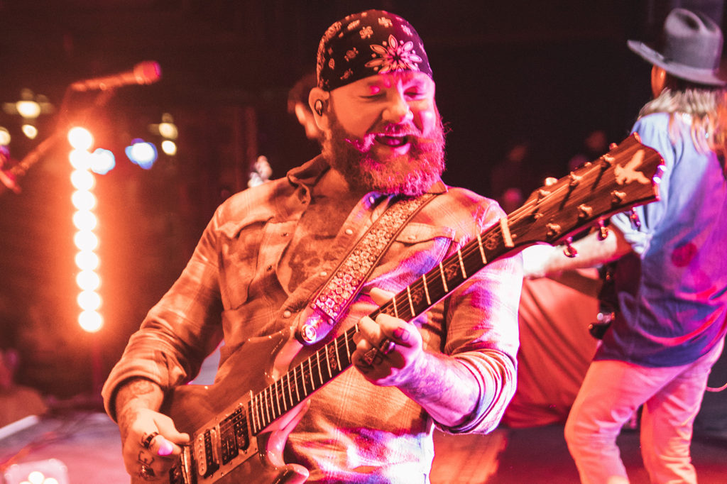 A band member playing Guitar on stage